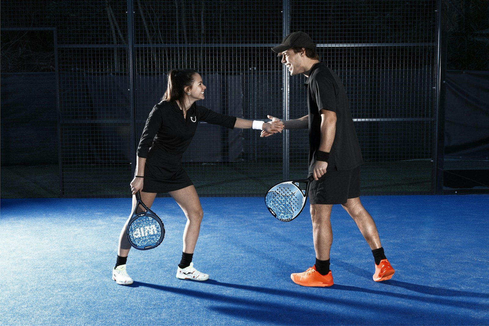 a man and woman shaking hands on a tennis court